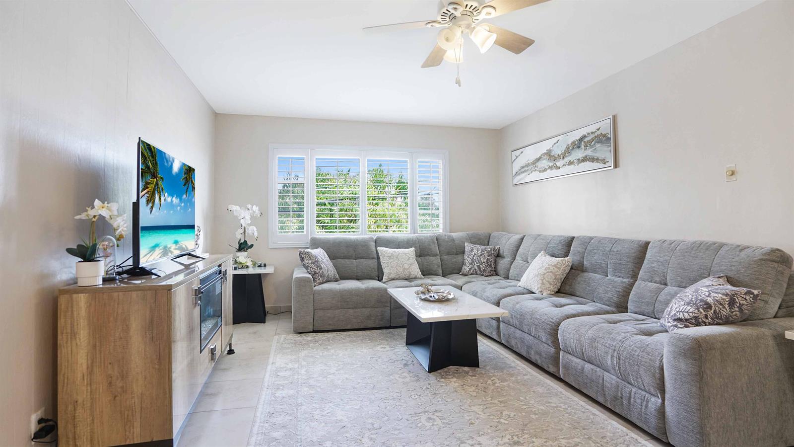 A living room features a grey sectional sofa, a coffee table, and a television console — 400 S Cypress Road # 428, Pompano Beach FL 33060, POMPANO BEACH, FL