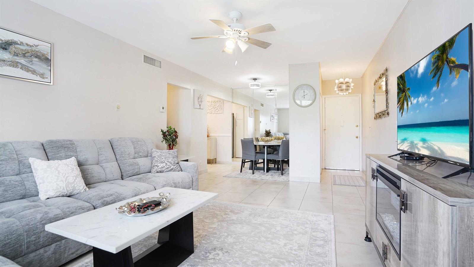 A living room with a grey sofa, marble coffee table, and a television on a console — 400 S Cypress Road # 428, Pompano Beach FL 33060, POMPANO BEACH, FL