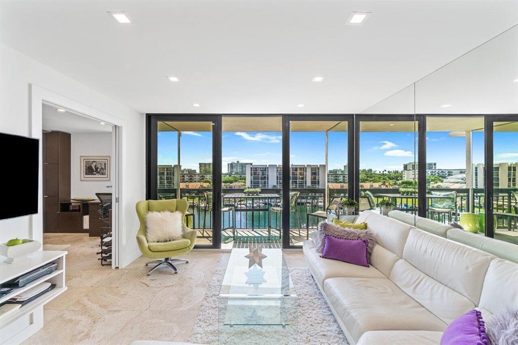 A living room with a white sofa, green armchair, glass coffee table, and balcony view — 2707 N Ocean Boulevard # D603, Boca Raton FL 33431, BOCA RATON, FL