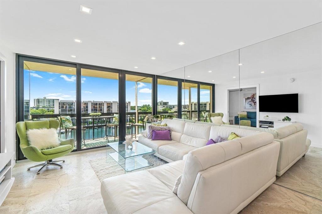 A living room features a white sectional sofa, a green armchair, and a mirrored wall — 2707 N Ocean Boulevard # D603, Boca Raton FL 33431, BOCA RATON, FL