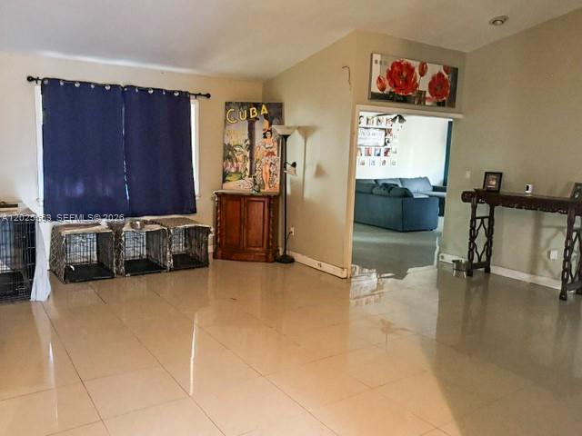 This living room features tile flooring, dark blue curtains, and a doorway leading to another room — 21705 SW 99th Ave, Cutler Bay FL 33190, CUTLER BAY, FL