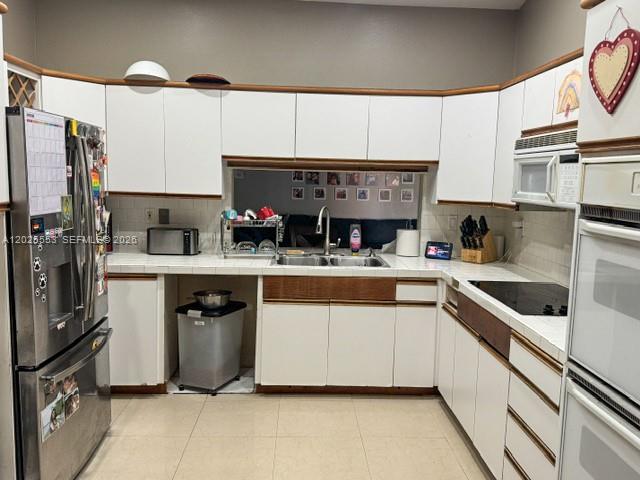 A kitchen features white cabinets with wood trim, stainless steel appliances, and tiled countertops — 21705 SW 99th Ave, Cutler Bay FL 33190, CUTLER BAY, FL