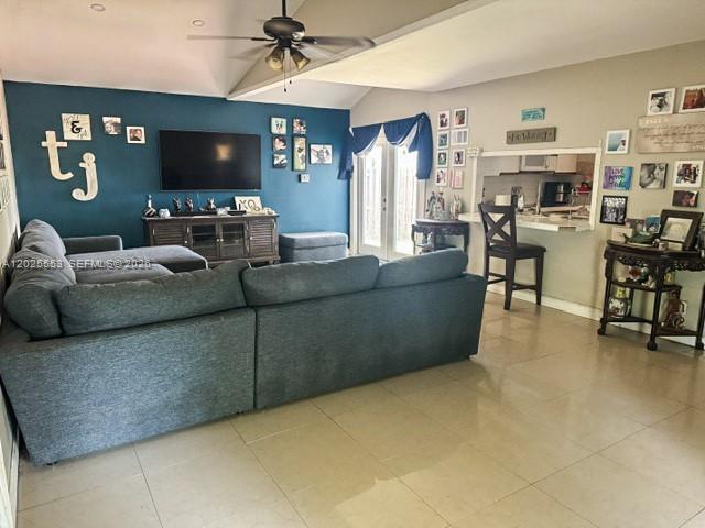A living room features a large gray sectional sofa, a television, and tile flooring — 21705 SW 99th Ave, Cutler Bay FL 33190, CUTLER BAY, FL