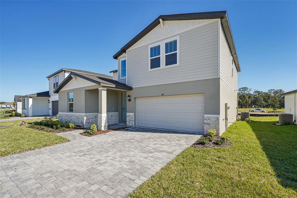 A two-story house with a paved driveway, a two-car garage, and stone veneer accents — 843 SUNSHOWER DRIVES, LADY LAKE, FL