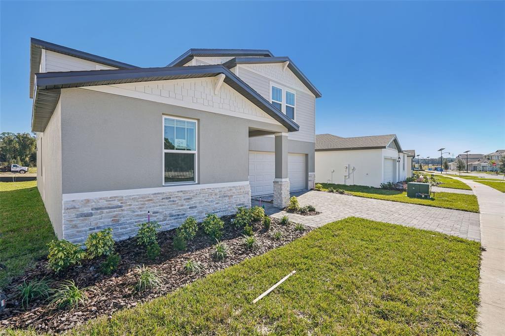 A two-story house with a stone-accented facade, gray siding, and a paved driveway — 843 SUNSHOWER DRIVES, LADY LAKE, FL