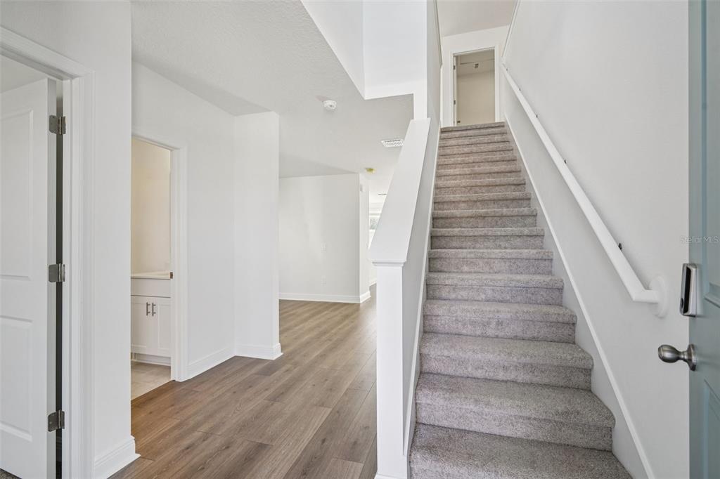 An interior view shows a carpeted staircase next to a hallway with wood-look flooring — 843 SUNSHOWER DRIVES, LADY LAKE, FL