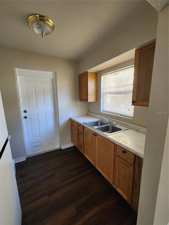 A kitchen features wood cabinets, a double-basin sink, white countertops, and dark wood flooring — 2219 HIGHLAND STREET UNIT 1, ST PETERSBURG, FL