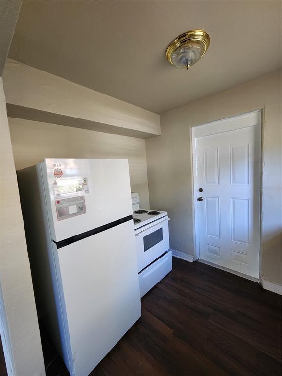 A kitchen features a white refrigerator, a white electric stove, and a white door — 2219 HIGHLAND STREET UNIT 1, ST PETERSBURG, FL