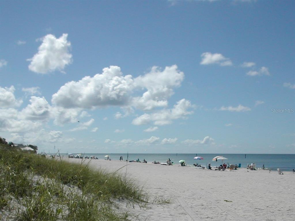 A wide, sandy beach with dunes, beach umbrellas, and people under a blue sky — 12319 BONITA PLACE, PLACIDA, FL