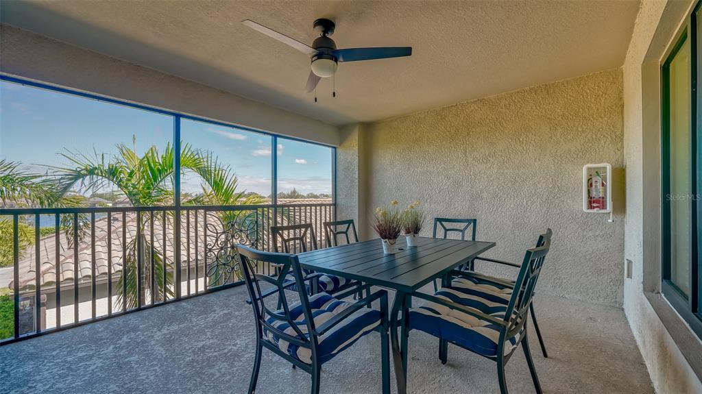 A covered balcony features a dining set, a ceiling fan, and a screened-in view — 5624 PALMER CIRCLE UNIT 203, BRADENTON, FL