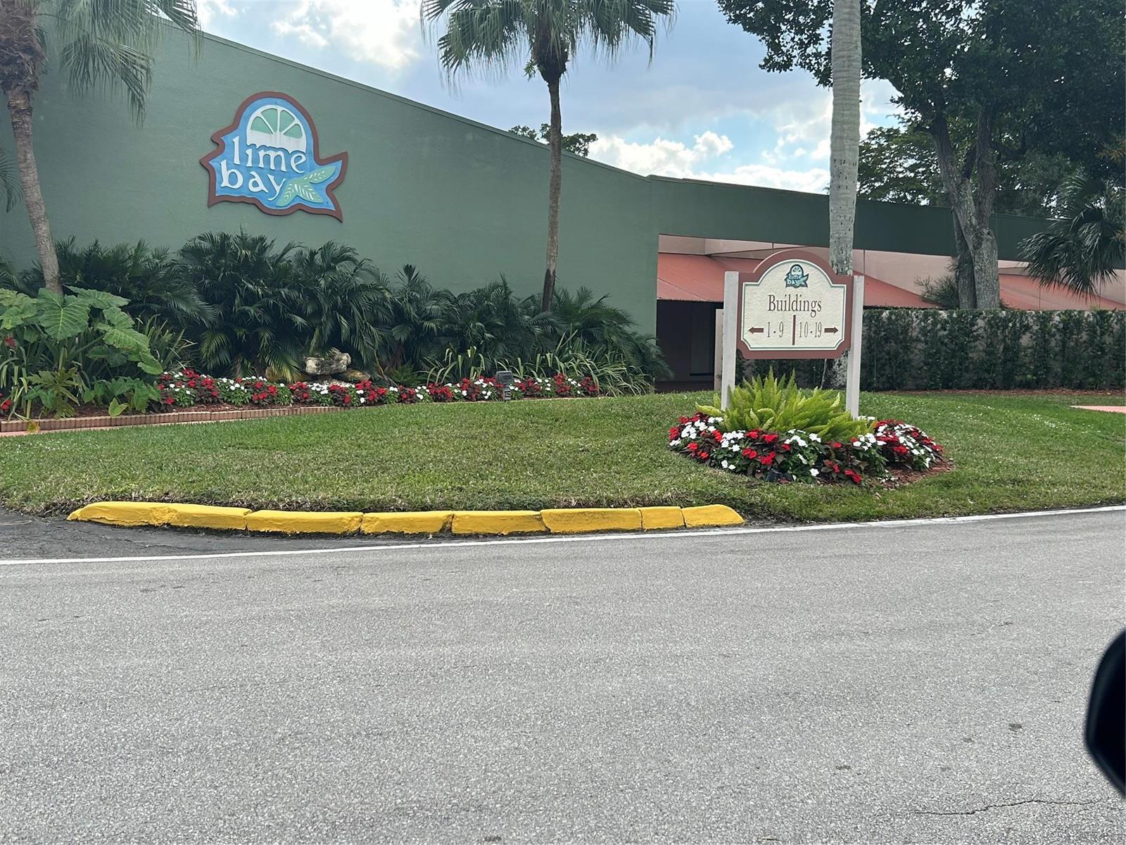 A green building with a Lime Bay sign and a directional sign for residential buildings — 9080 Lime Bay Boulevard # 305, Tamarac FL 33312, TAMARAC, FL