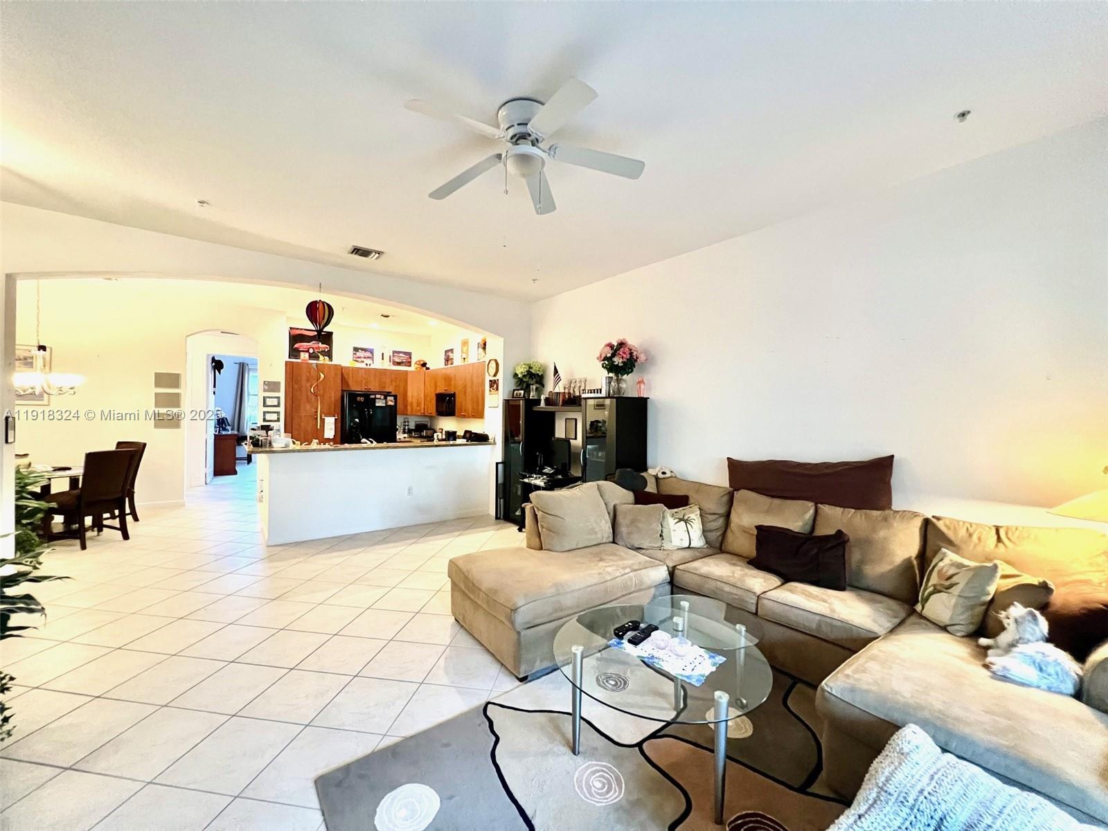 A living room with a sectional sofa and glass coffee table opens to a kitchen — 2901 NW 126th Ave # 415, Sunrise FL 33323, SUNRISE, FL