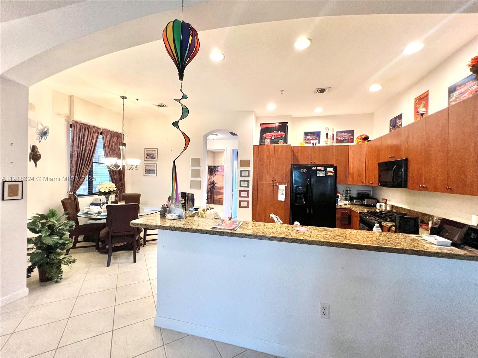 This kitchen and dining area features wood cabinets, granite countertops, and tile flooring — 2901 NW 126th Ave # 415, Sunrise FL 33323, SUNRISE, FL
