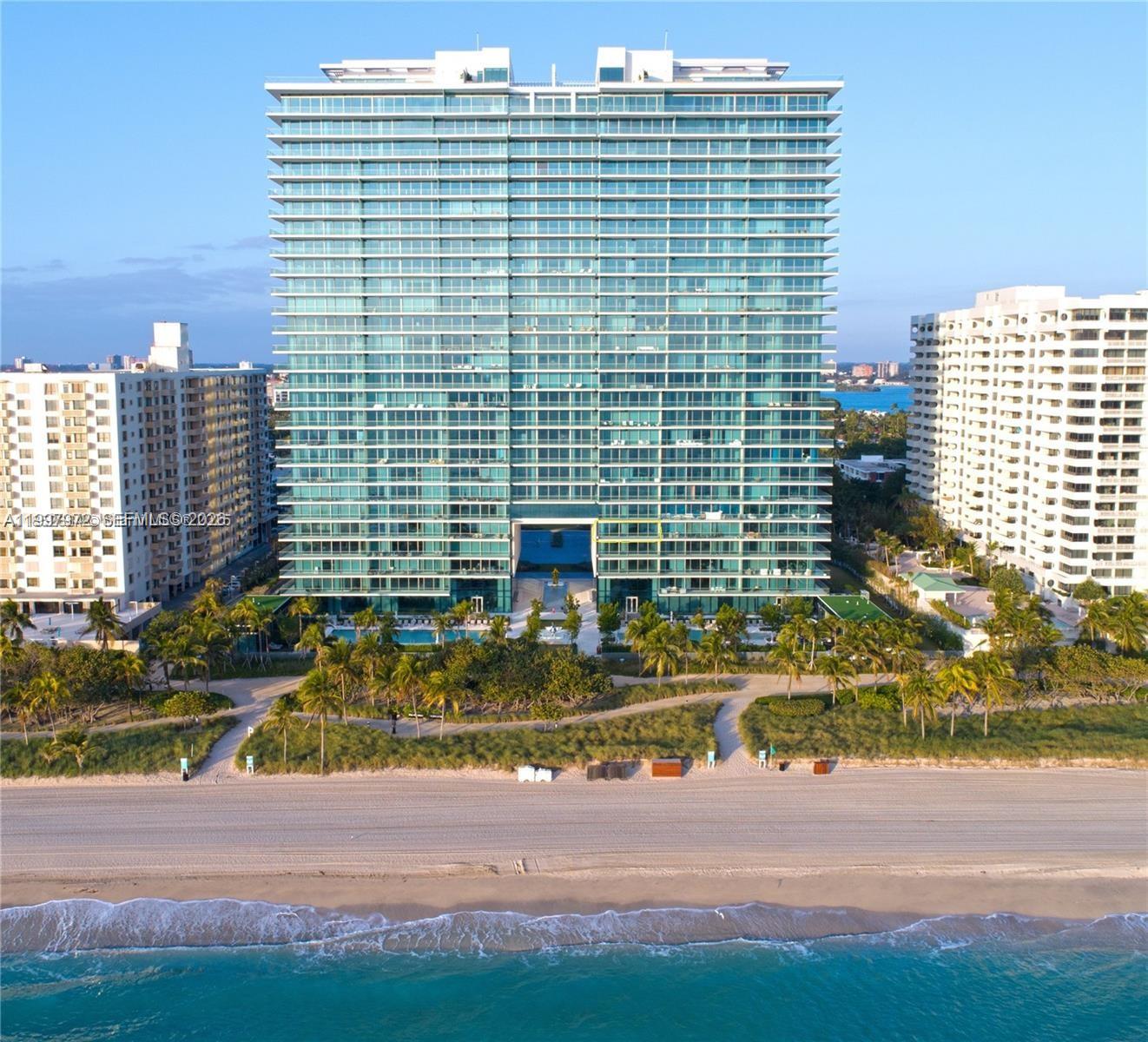 An aerial view of a modern glass high-rise condominium building situated on a sandy beach — 10203 Collins Ave # 1001, Bal Harbour FL 33154, BAL HARBOUR, FL