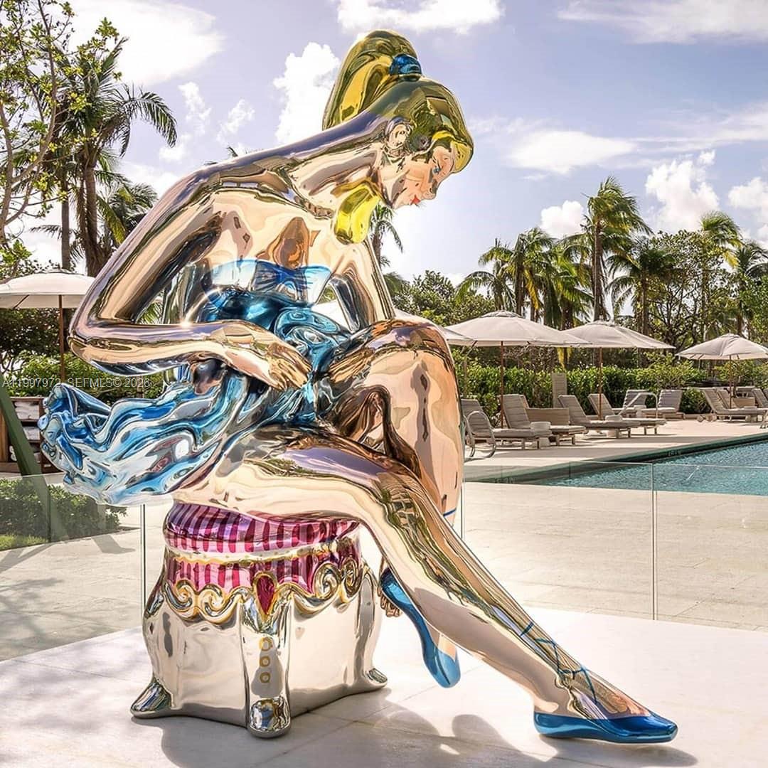 A large, reflective metallic sculpture of a seated ballerina sits on a patio by a pool — 10203 Collins Ave # 1001, Bal Harbour FL 33154, BAL HARBOUR, FL