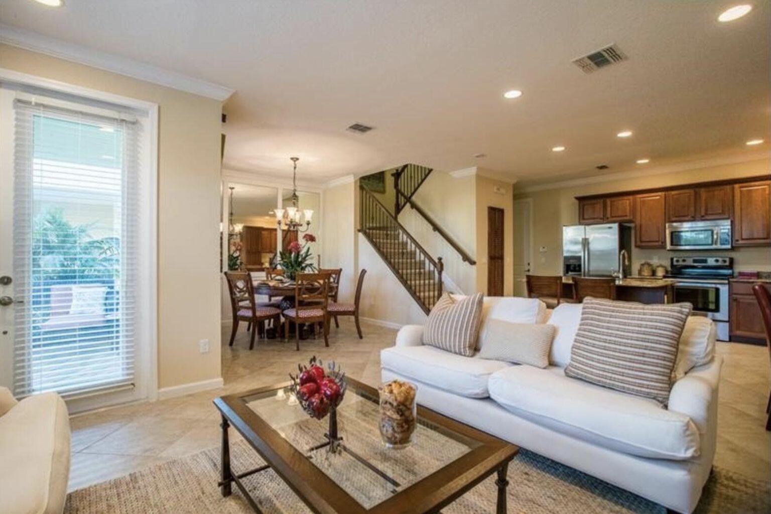 A living room with a white sofa, glass coffee table, dining area, and wooden staircase — 1485 NW 48th Drive, Boca Raton FL 33431, BOCA RATON, FL