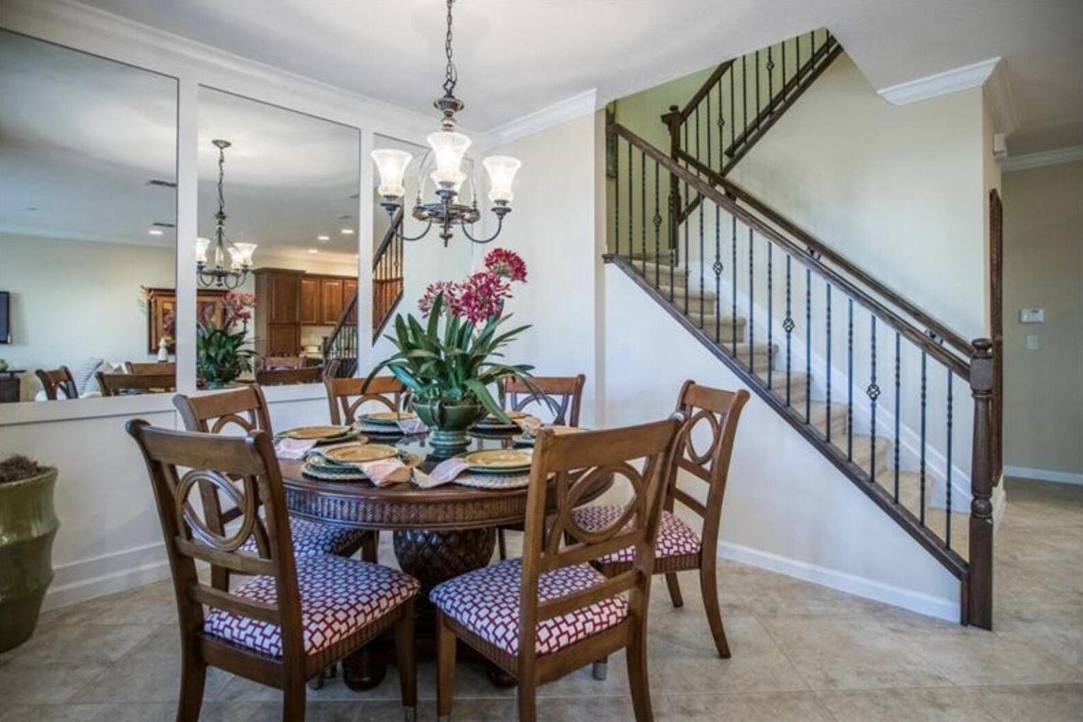 A dining room features a round wooden table, patterned chairs, a chandelier, and a staircase — 1485 NW 48th Drive, Boca Raton FL 33431, BOCA RATON, FL