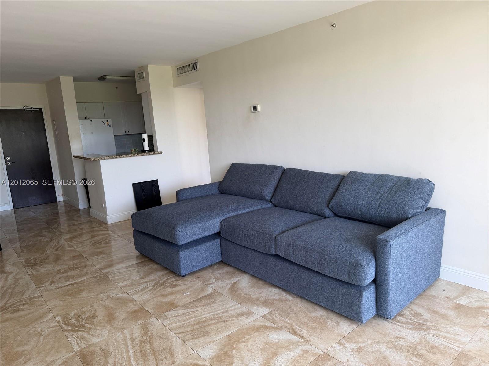A blue sectional sofa sits on a tiled floor in a room with an open kitchen — 1500 Bay Rd # 318S, Miami Beach FL 33139, MIAMI BEACH, FL