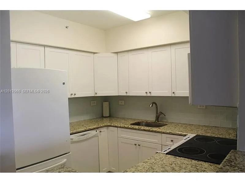 A kitchen features white cabinets, granite countertops, a white refrigerator, and a stainless steel sink — 1500 Bay Rd # 318S, Miami Beach FL 33139, MIAMI BEACH, FL