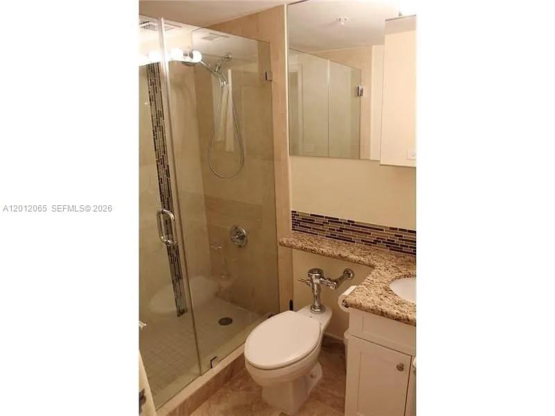 A bathroom features a glass-enclosed shower, a toilet with a flushometer, and granite countertops — 1500 Bay Rd # 318S, Miami Beach FL 33139, MIAMI BEACH, FL