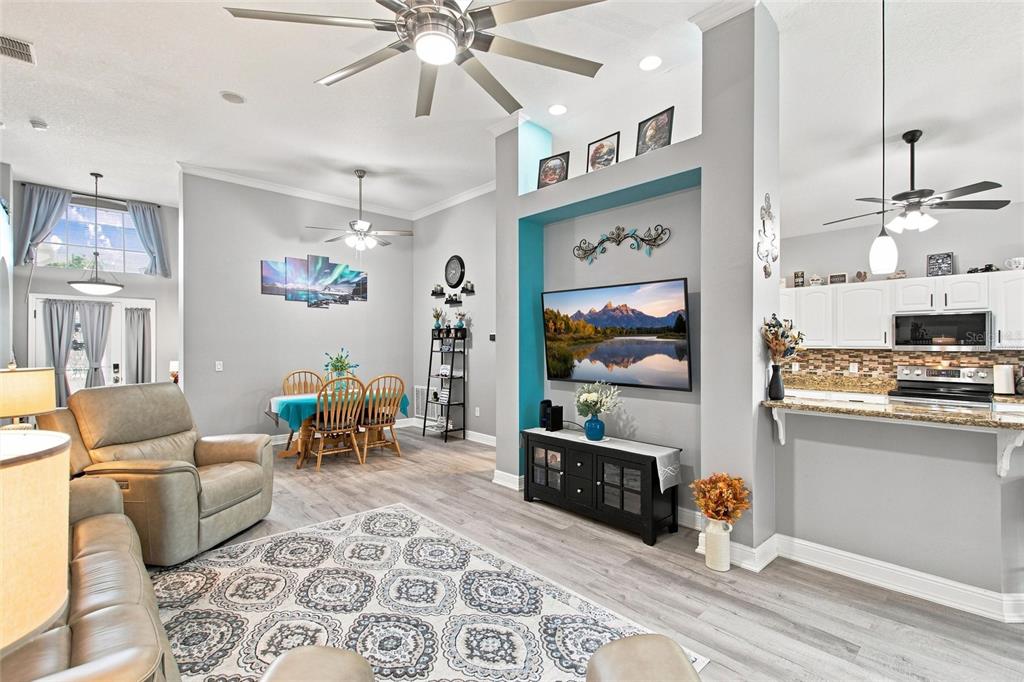 A living room with light wood floors, a teal accent wall, and an open kitchen — 919 ASHTON DR, DAVENPORT, FL
