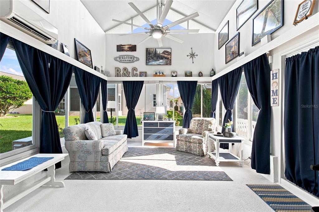 A sunroom features a vaulted ceiling with a large fan, dark curtains, and floral furniture — 919 ASHTON DR, DAVENPORT, FL