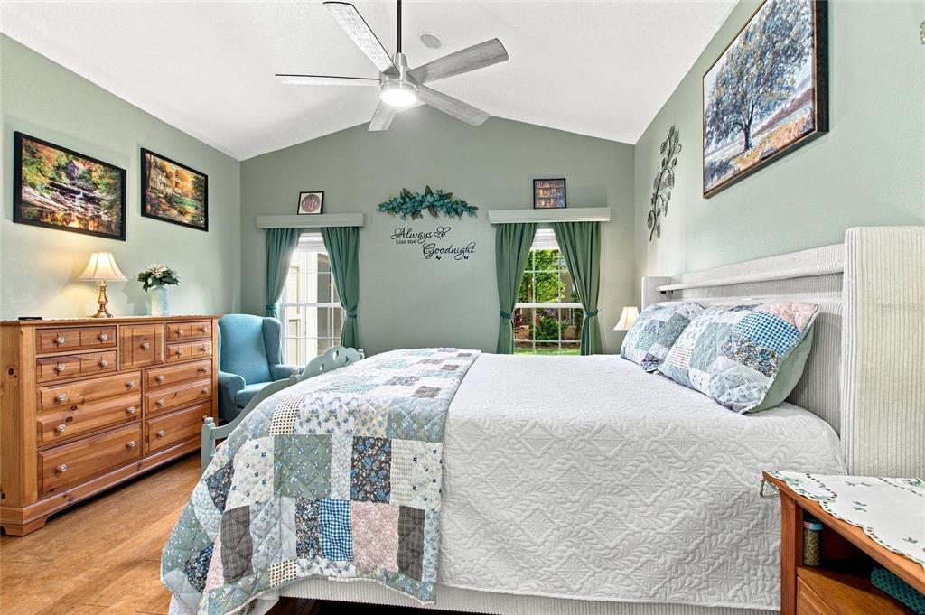 A bedroom features a bed with a patchwork quilt, green walls, and a ceiling fan — 919 ASHTON DR, DAVENPORT, FL