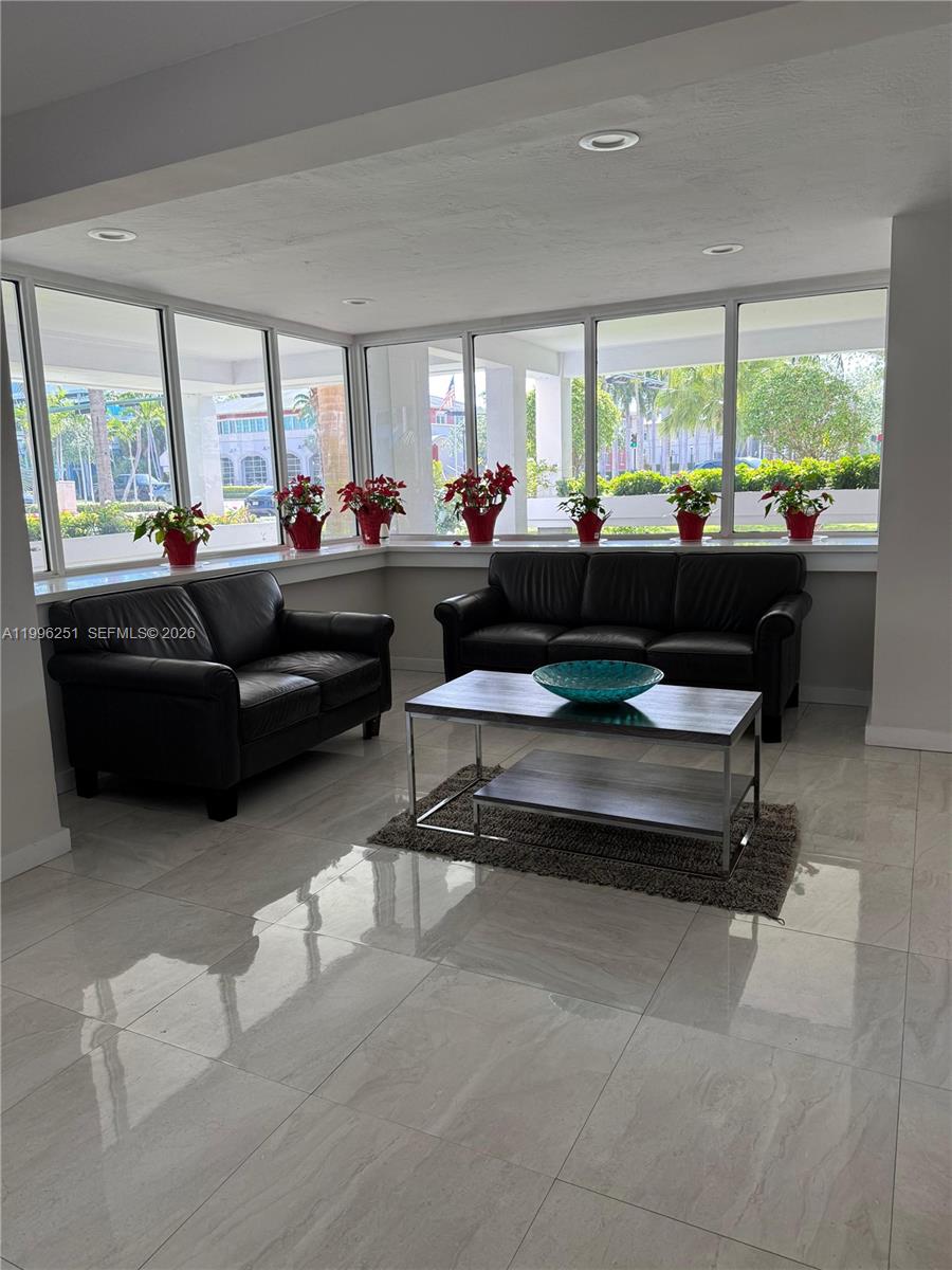 A living area features black leather sofas, a coffee table, and windows with potted plants — 555 Crandon Blvd # 43, Key Biscayne FL 33149, KEY BISCAYNE, FL