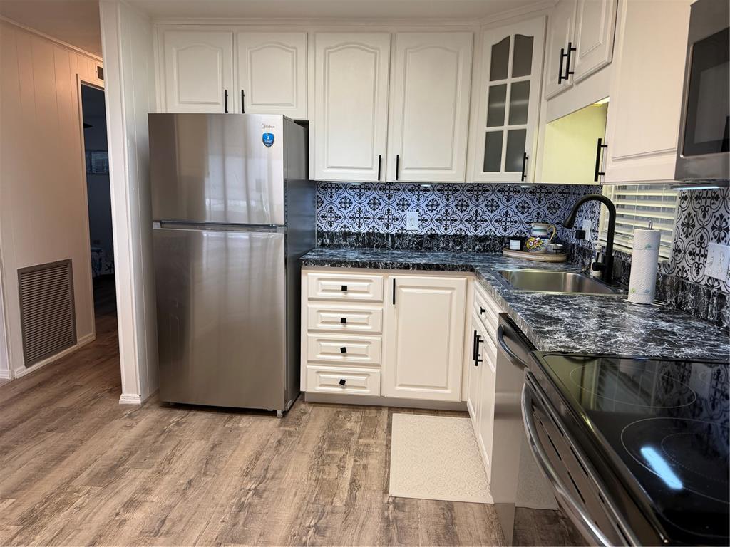 A kitchen with white cabinets, stainless steel appliances, patterned backsplash, and dark marble-look countertops — 12260 HALLMARK AVENUE, BROOKSVILLE, FL