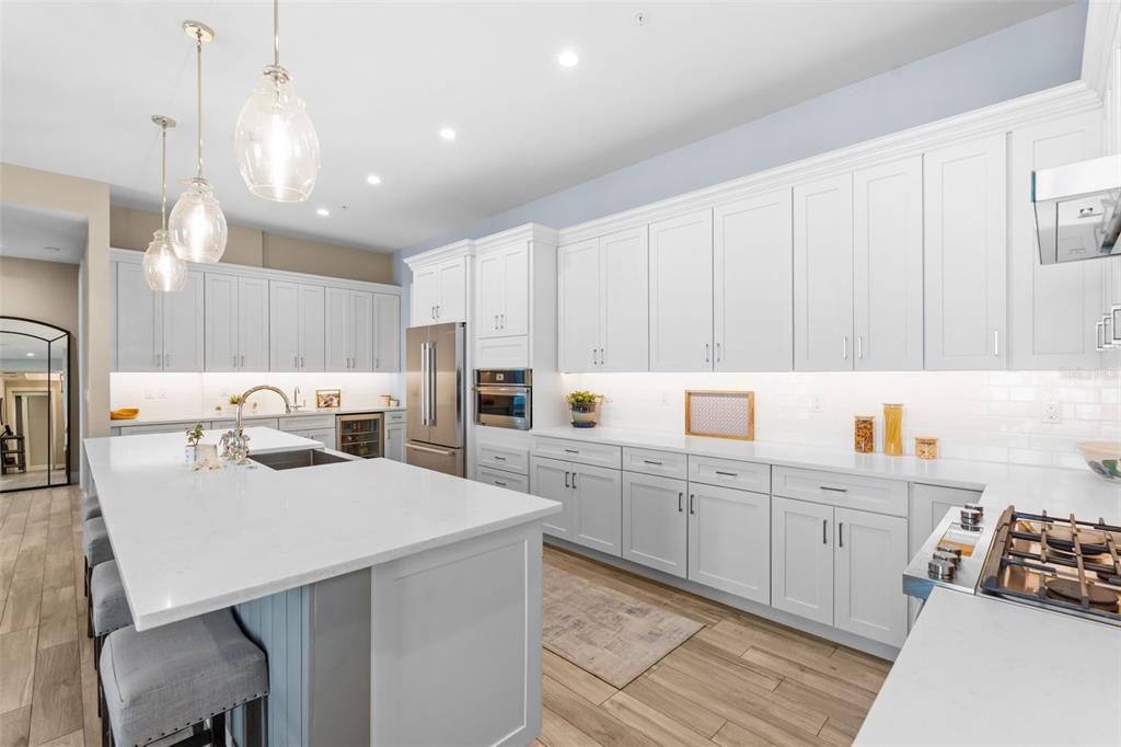 A modern kitchen features white cabinetry, a large quartz island, and stainless steel appliances — 91 DAVIS BOULEVARD UNIT 204, TAMPA, FL