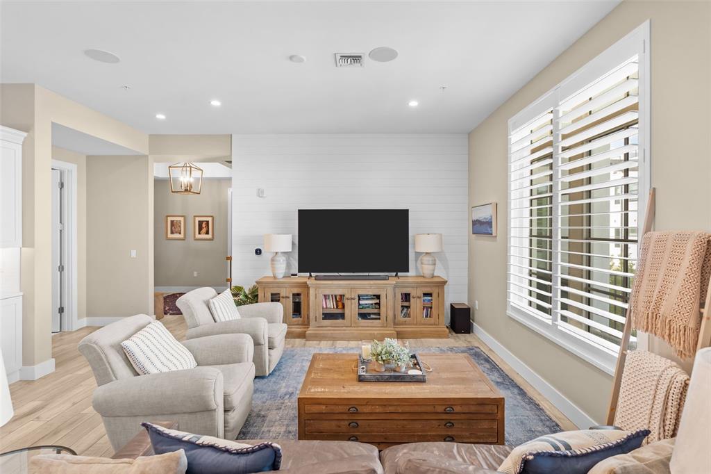 A living room features a shiplap accent wall, wooden media console, and a blue rug — 91 DAVIS BOULEVARD UNIT 204, TAMPA, FL