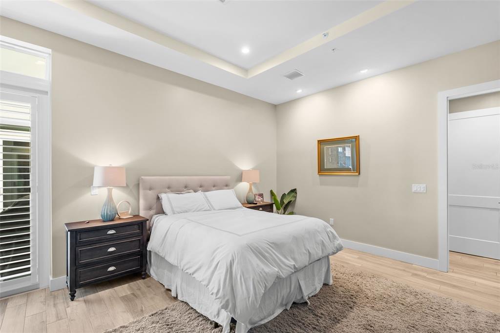 A bedroom features a bed with a tufted headboard, two nightstands, and light-colored flooring — 91 DAVIS BOULEVARD UNIT 204, TAMPA, FL