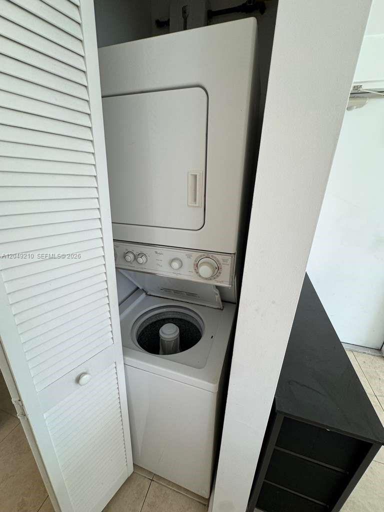 A white stacked washer and dryer unit is located inside a small closet — 7130 Rue Versailles # 6, Miami Beach FL 33141, MIAMI BEACH, FL