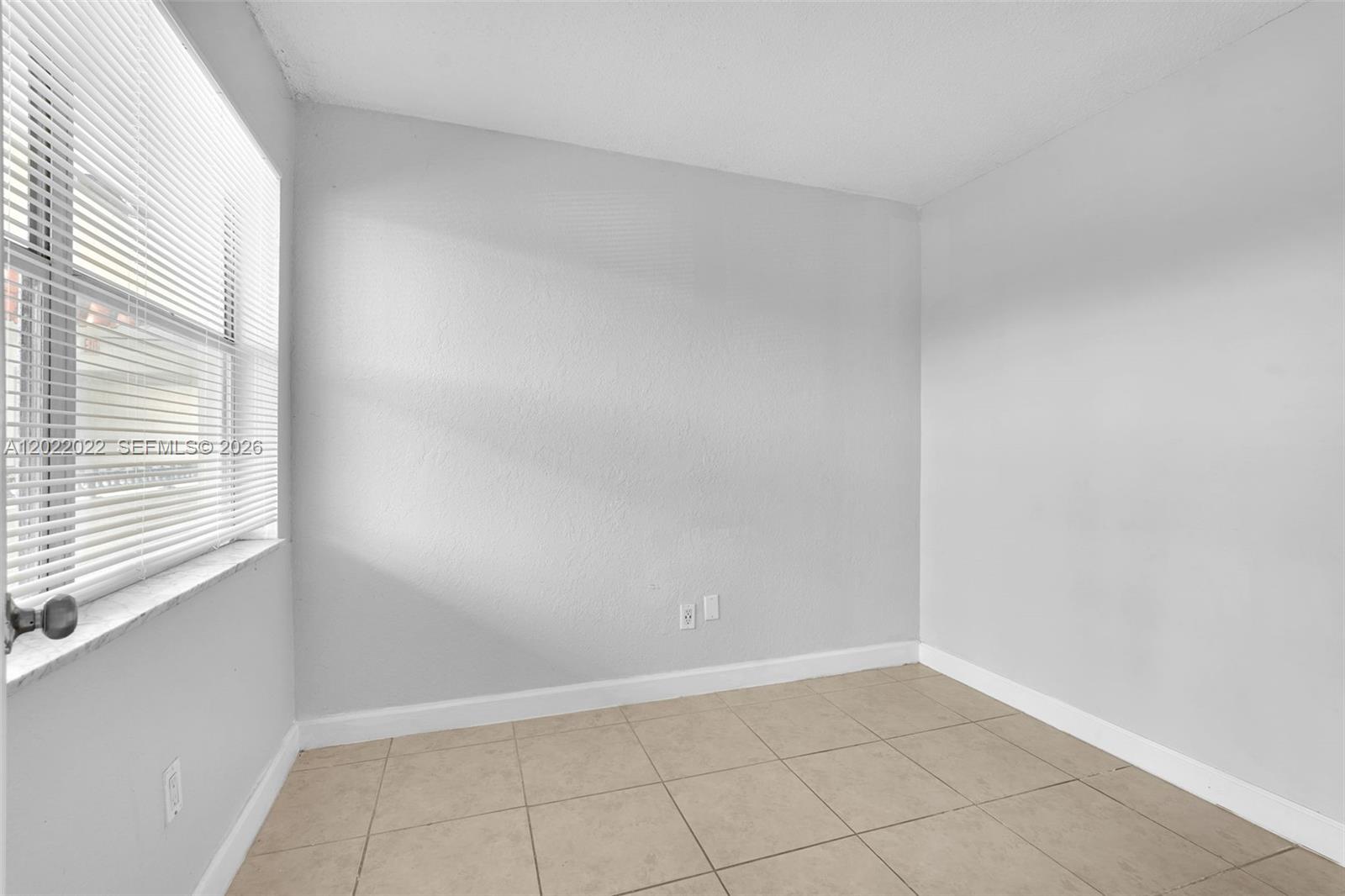An empty room features light gray walls, a window with white blinds, and tiled flooring — 400 NW 65th Ave # 213, Margate FL 33063, MARGATE, FL