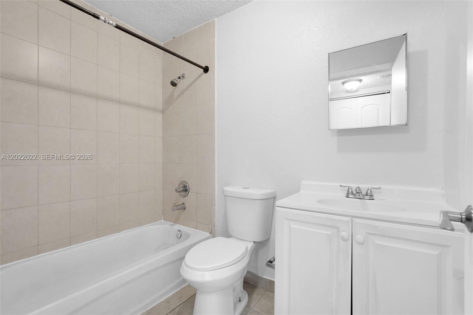 A bathroom features a white vanity, a toilet, and a bathtub with beige tiled walls — 400 NW 65th Ave # 213, Margate FL 33063, MARGATE, FL