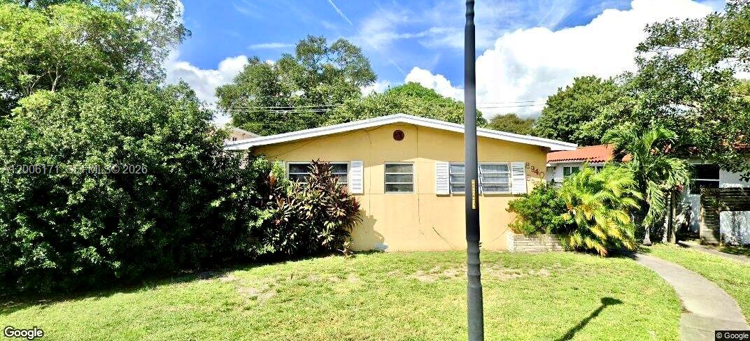 A single-story yellow house with a lawn and trees under a blue sky — EL PORTAL, FL