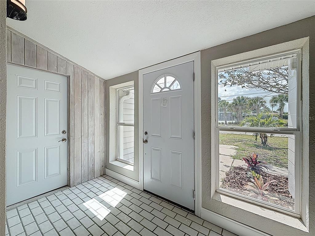 A sunroom features white tile flooring, wood-paneled walls, two white doors, and large windows — 4221 SHORE ACRES BOULEVARD NE, ST PETERSBURG, FL