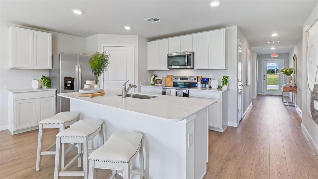 A modern kitchen features white cabinets, a central island with bar seating, and wood flooring — 1529 HARMON DRIVE, PORT CHARLOTTE, FL