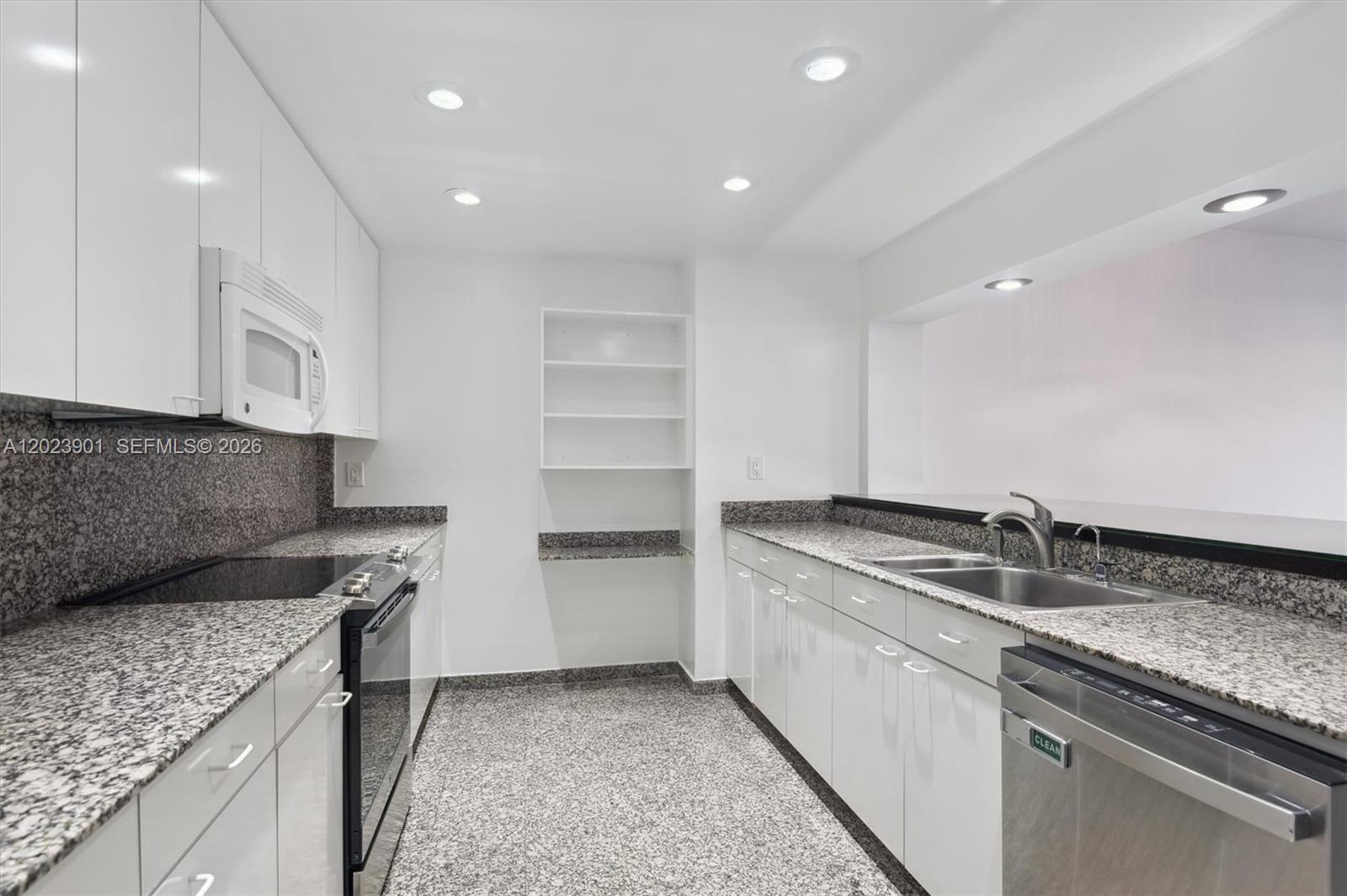 A galley kitchen features white cabinets, granite countertops, stainless steel appliances, and recessed lighting — 151 Crandon Blvd # 120, Key Biscayne FL 33149, KEY BISCAYNE, FL