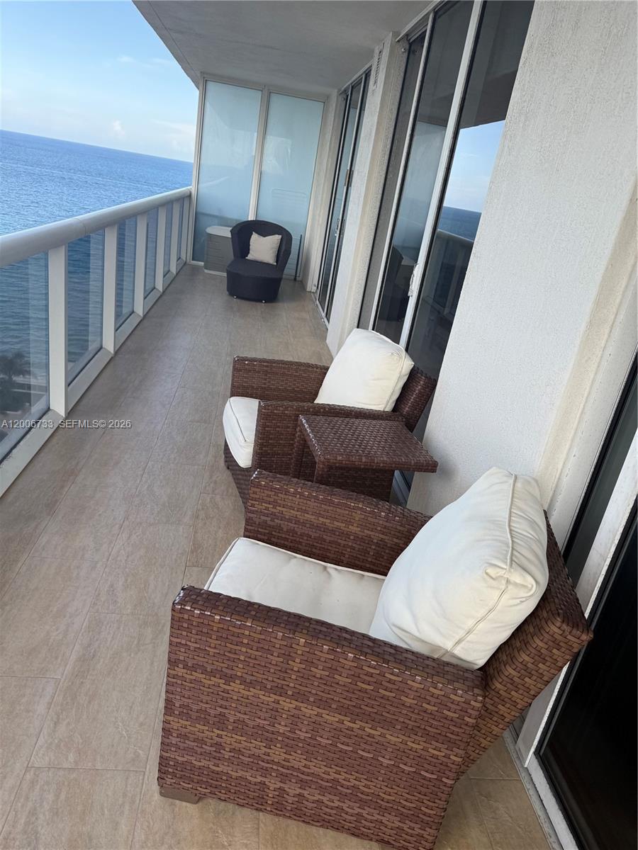 A balcony with wicker chairs, white cushions, and a view of the ocean — 1830 S Ocean Dr # 1708, Hallandale Beach FL 33009, HALLANDALE BEACH, FL