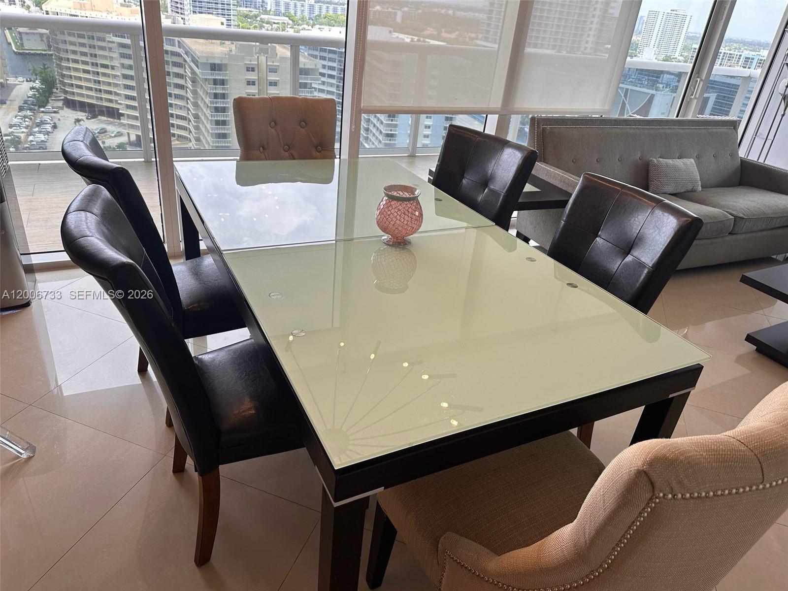 A dining room features a glass-topped table, mixed seating, and floor-to-ceiling windows with city views — 1830 S Ocean Dr # 1708, Hallandale Beach FL 33009, HALLANDALE BEACH, FL