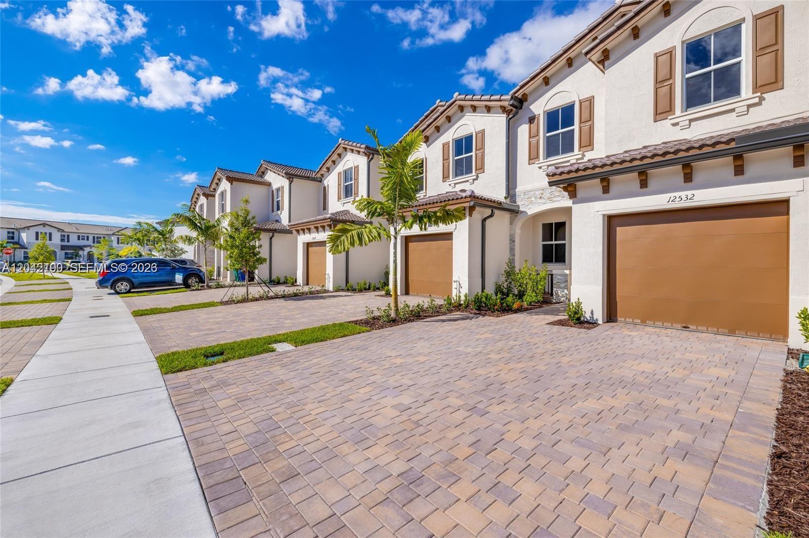 A row of two-story townhomes features beige stucco facades, brown garage doors, and paver driveways — 12532 NW 23rd Pl, Miami FL 33167, MIAMI, FL