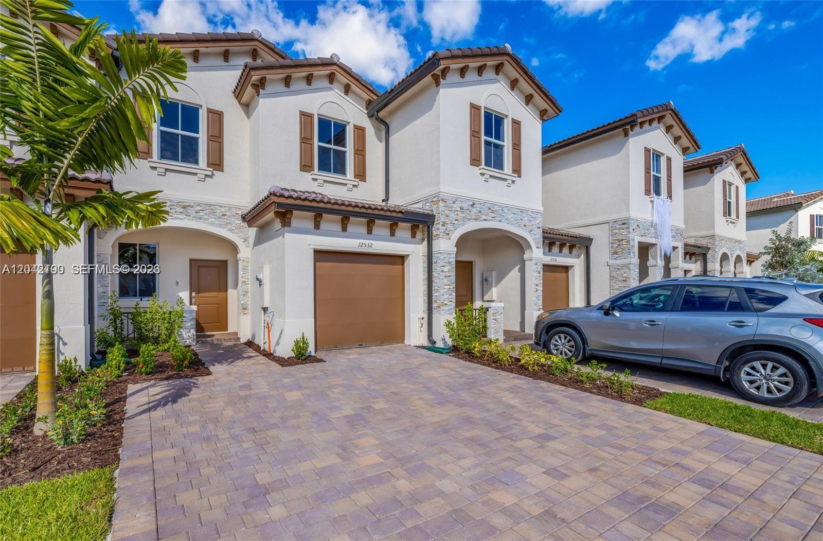 A row of two-story townhomes features stucco facades, stone accents, and paved driveways — 12532 NW 23rd Pl, Miami FL 33167, MIAMI, FL