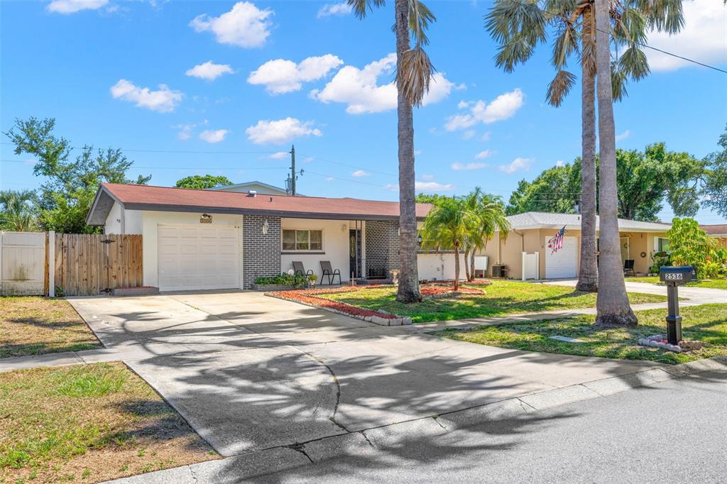 A single-story house with a brick facade, a garage, and palm trees in the front yard — 2536 KEENE PARK DRIVE, LARGO, FL