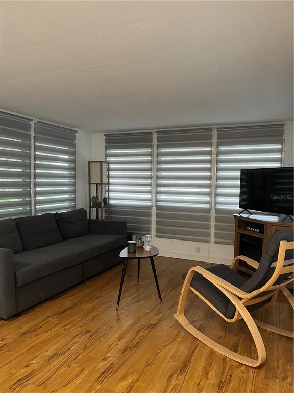 A living room features a dark sofa, a wooden rocking chair, and gray window shades — 1509 23RD AVENUE W, BRADENTON, FL
