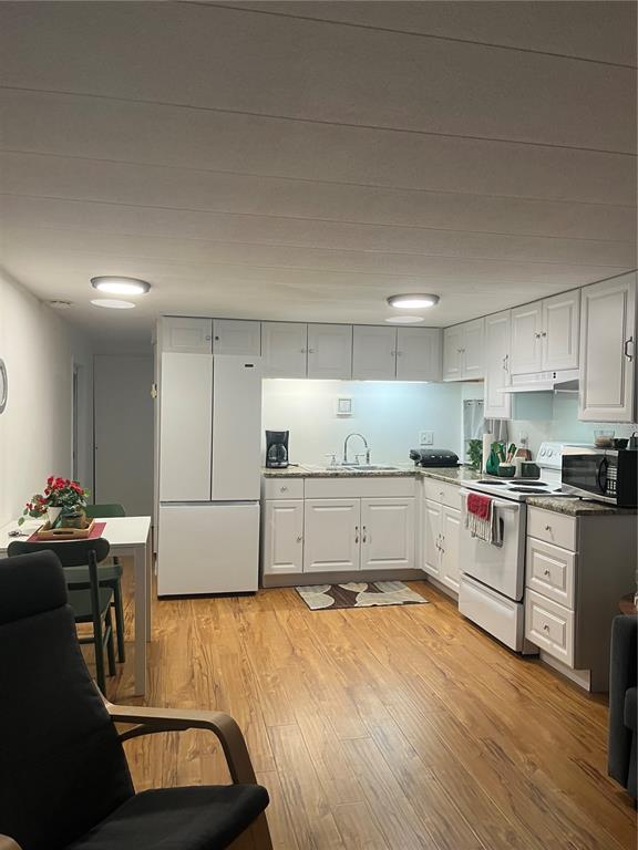 A kitchen with white cabinets, white appliances, and wood-look flooring in an open-concept space — 1509 23RD AVENUE W, BRADENTON, FL