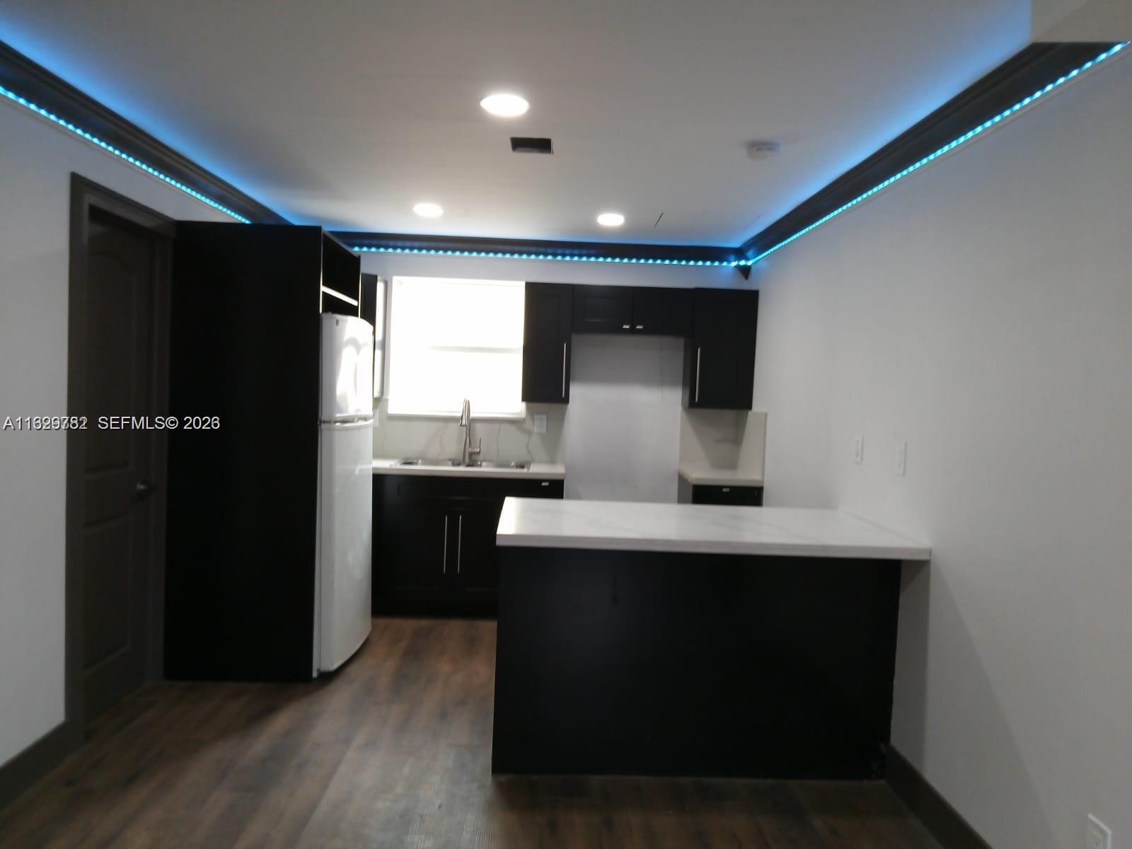 A kitchen features dark cabinets, a white countertop, a white refrigerator, and blue LED lighting — 2720 NW 29th St # 2720, Miami FL 33142, MIAMI, FL