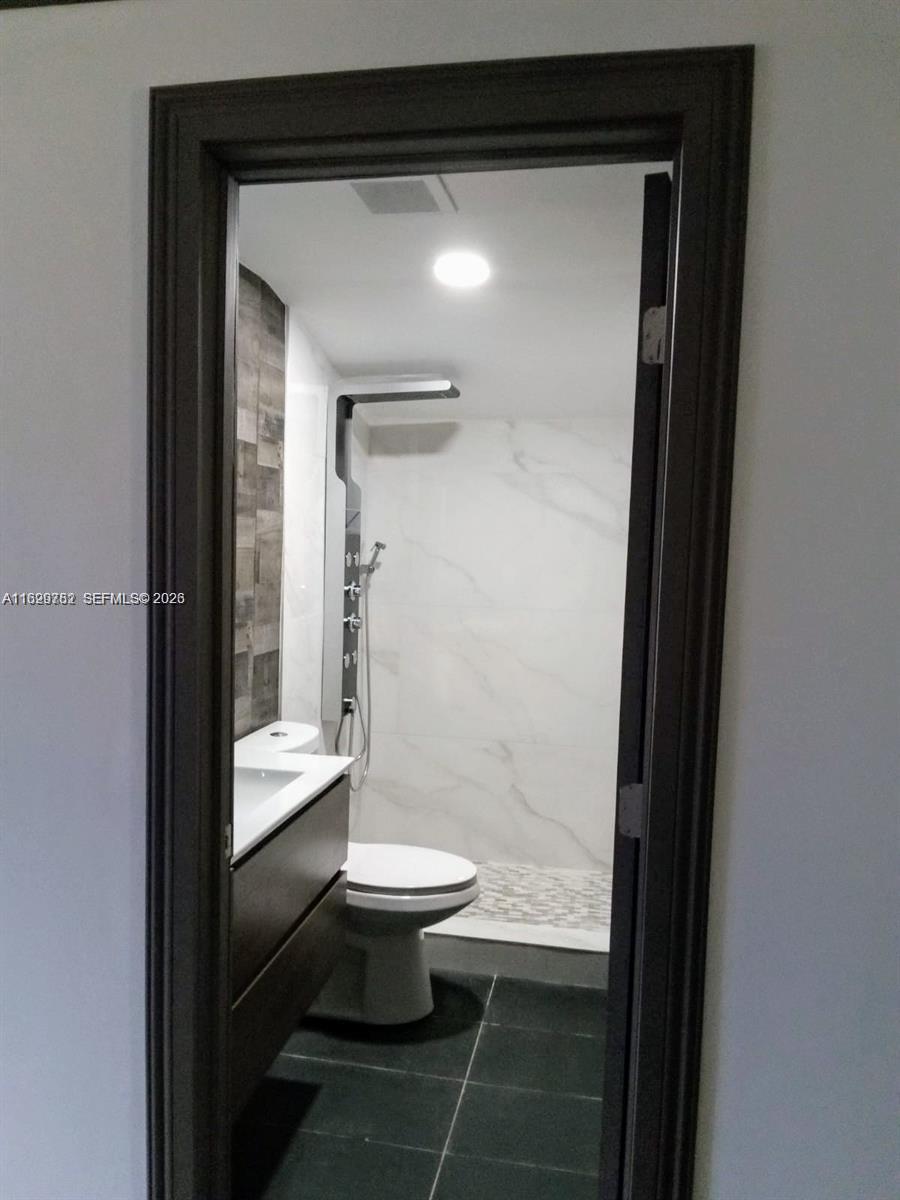 A bathroom features a walk-in shower with marble-look tile, a vanity, and a toilet — 2720 NW 29th St # 2720, Miami FL 33142, MIAMI, FL