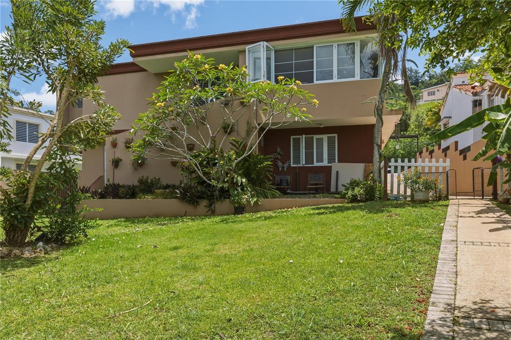 A two-story house with a tan exterior, a grassy yard, and a paved walkway — 149 YUISA ST.  LOMAS Lot 76, MANATI, PR