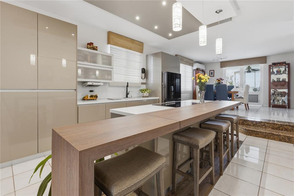 A modern kitchen features a wood-topped island, glossy beige cabinetry, and tile flooring — 149 YUISA ST.  LOMAS Lot 76, MANATI, PR